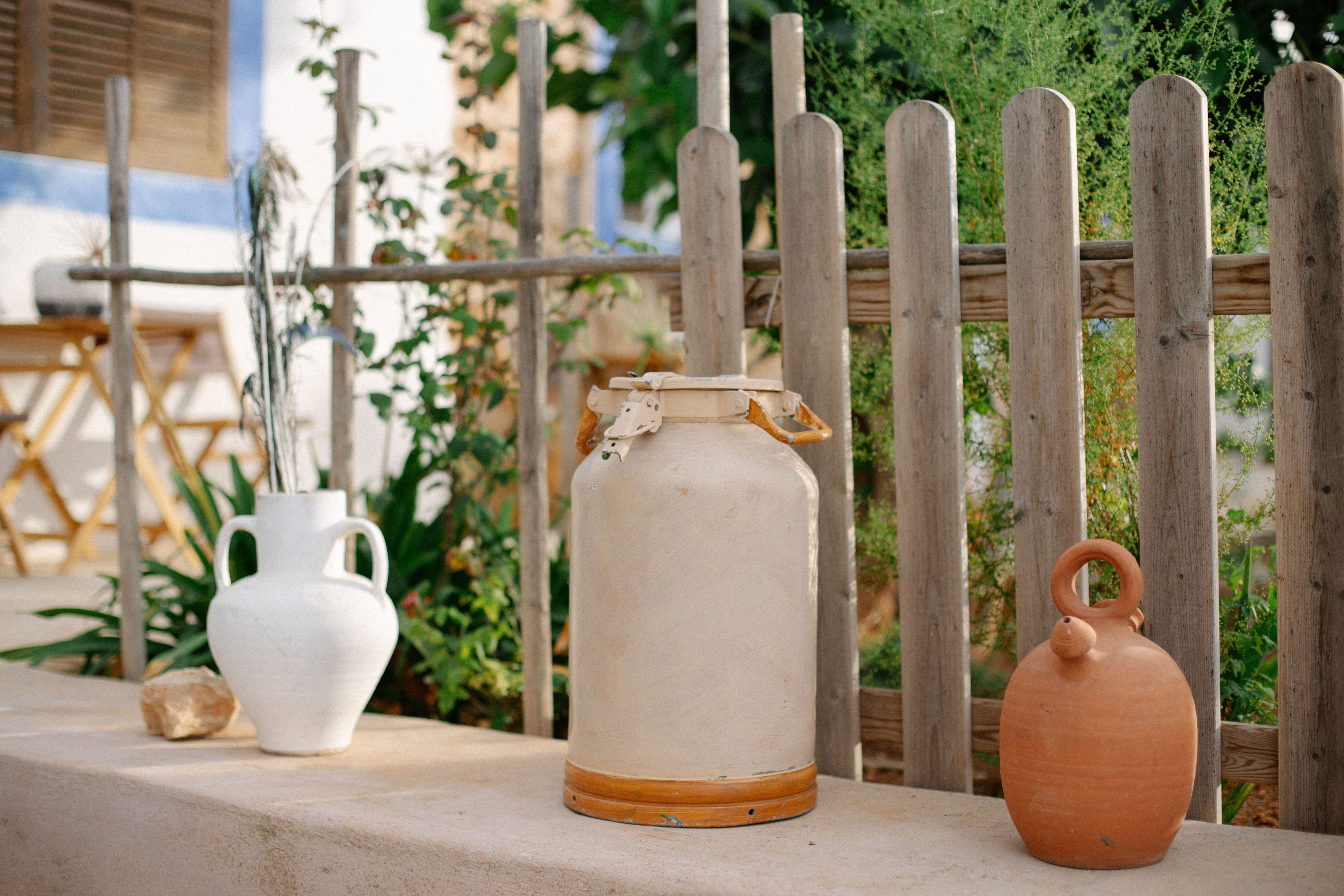 Rustic outdoor vignette with ceramic jugs and wooden fence in garden setting