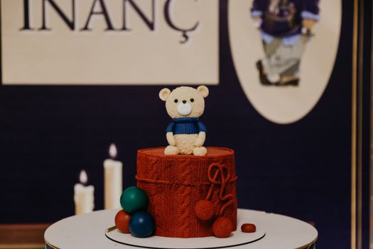 Charming red cake with teddy bear topper ideal for birthday celebrations.