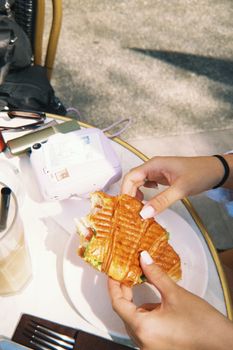 Person enjoying a sandwich outdoors at a cafe, capturing a casual and relaxed vibe.