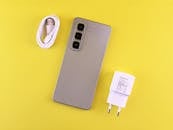 Stylish Smartphone with Charger on Yellow Background