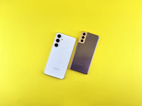 Two sleek smartphones on a bright yellow background, emphasizing modern technology and design.
