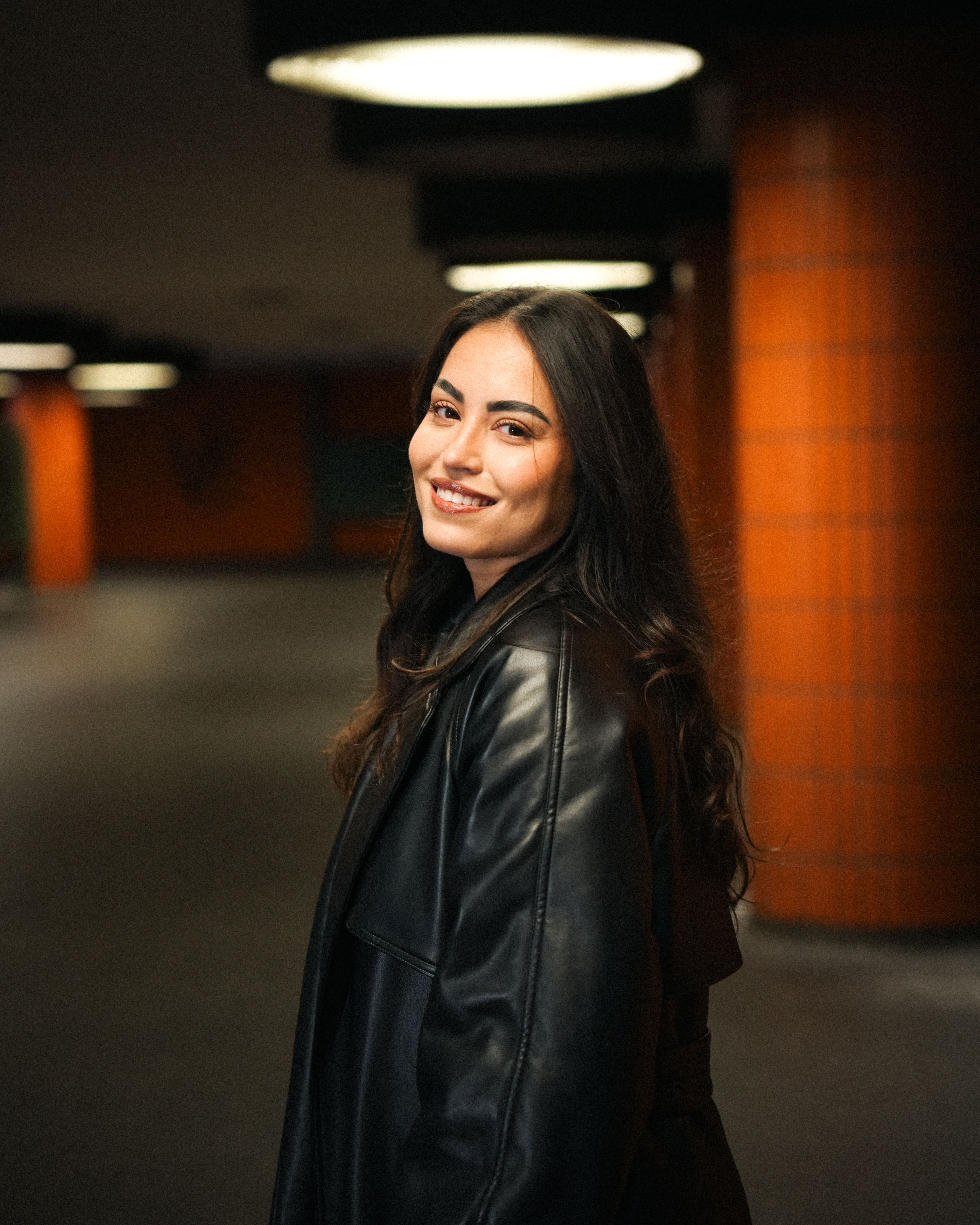 Smiling Woman in Black Leather Jacket in Urban Setting · Free Stock Photo