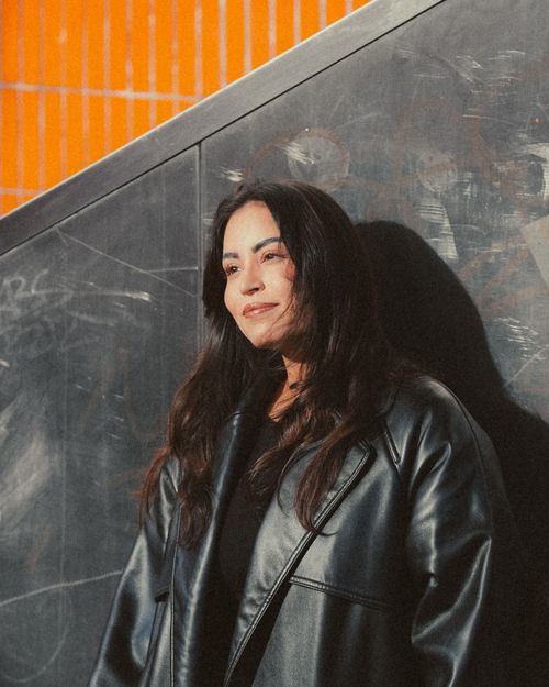 Free Woman in leather jacket against graffiti wall with orange pattern background. Stock Photo