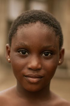 Close-up portrait of a young black girl with short hair and natural expression.