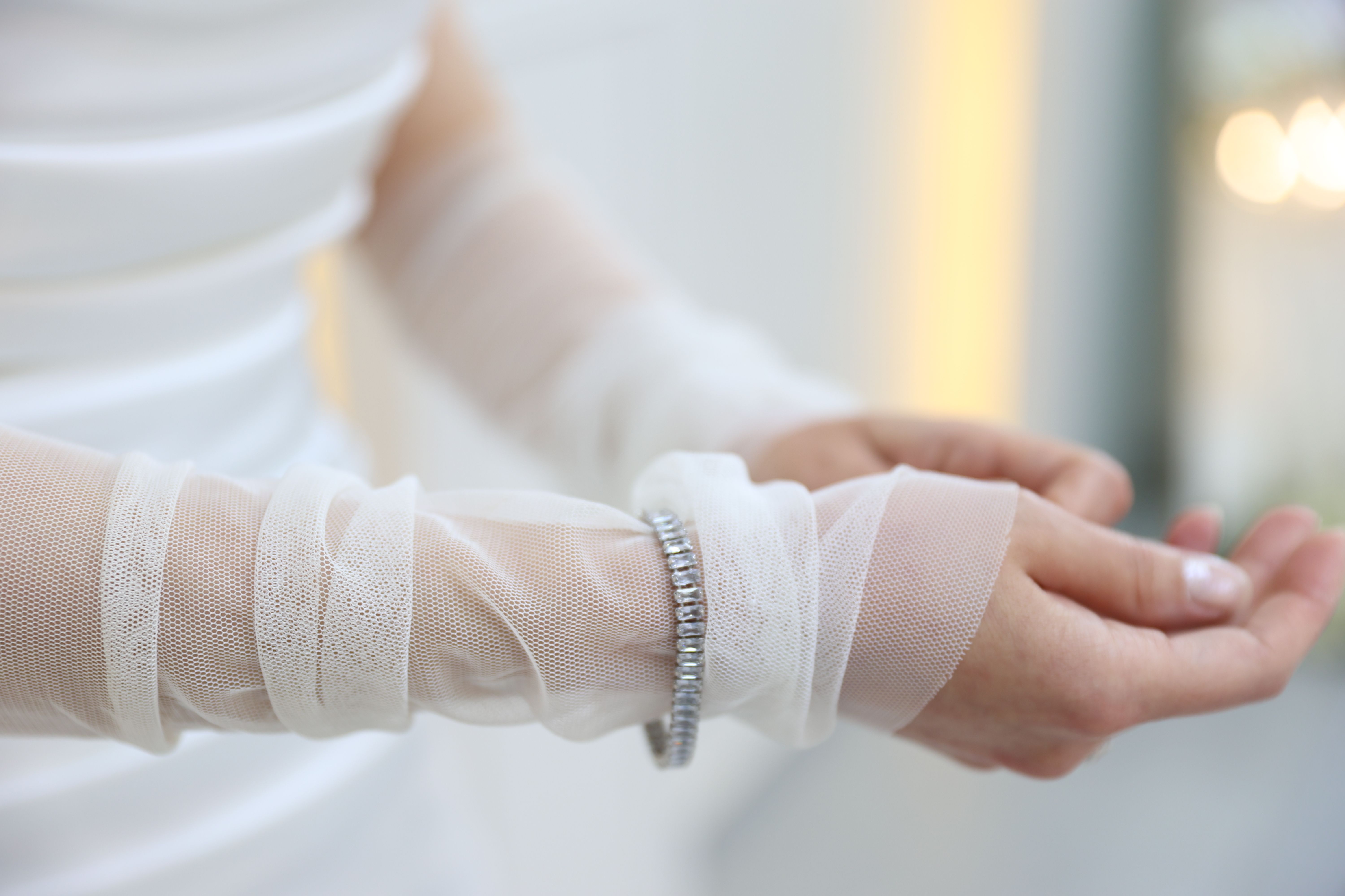 Close-up of a bride's sheer mesh sleeves and diamond bracelet showcasing elegant bridal fashion.