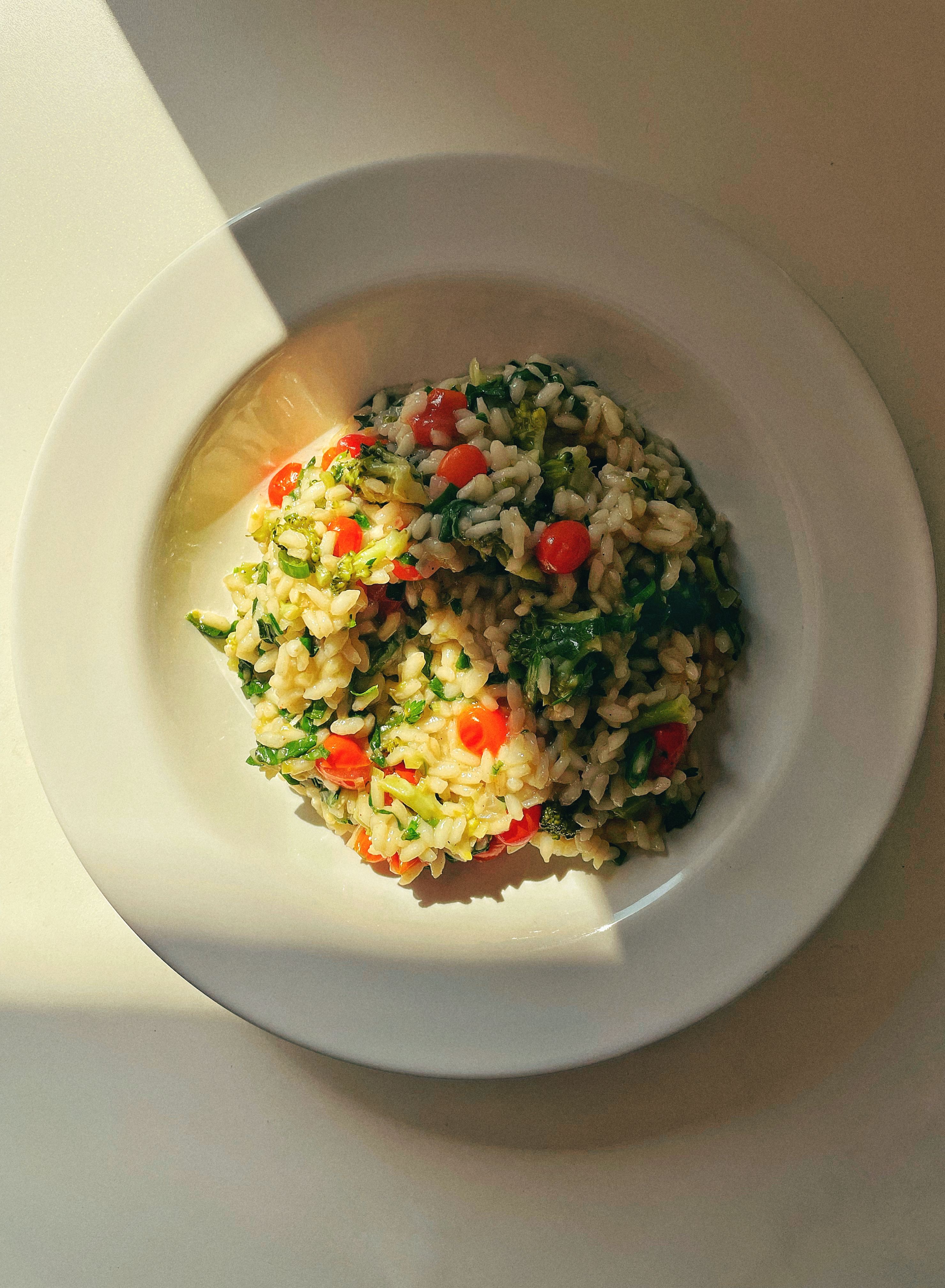 Top view of a vibrant vegan risotto with fresh vegetables on a plate.