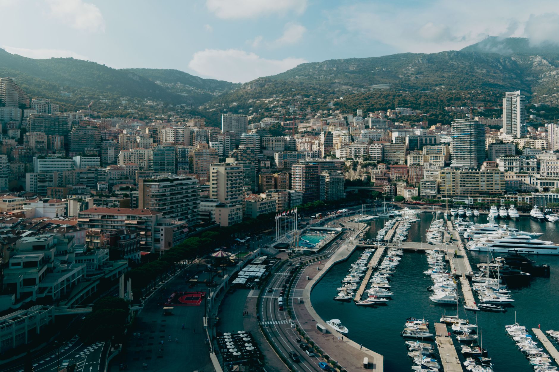 Stunning aerial view of Monaco cityscape with luxury yachts in the harbor under a sunny sky.