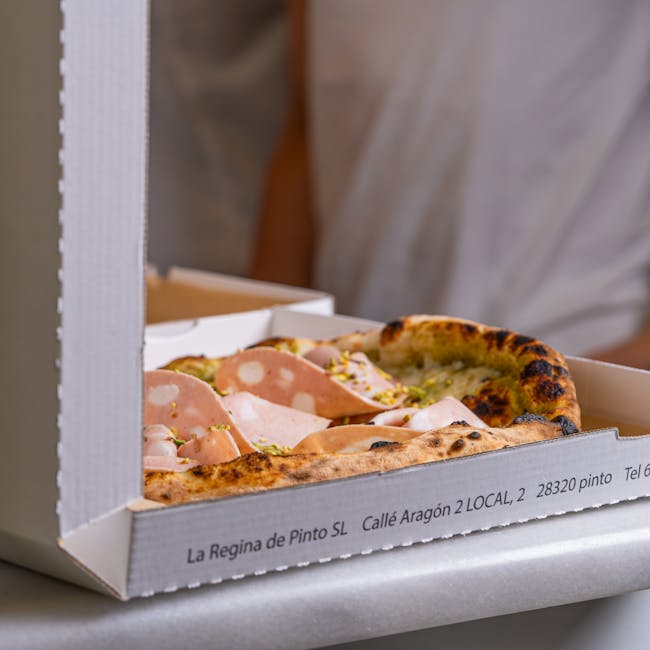Close-up of a fresh mortadella pizza in a takeout box, ready to serve. Ideal for food delivery concept.