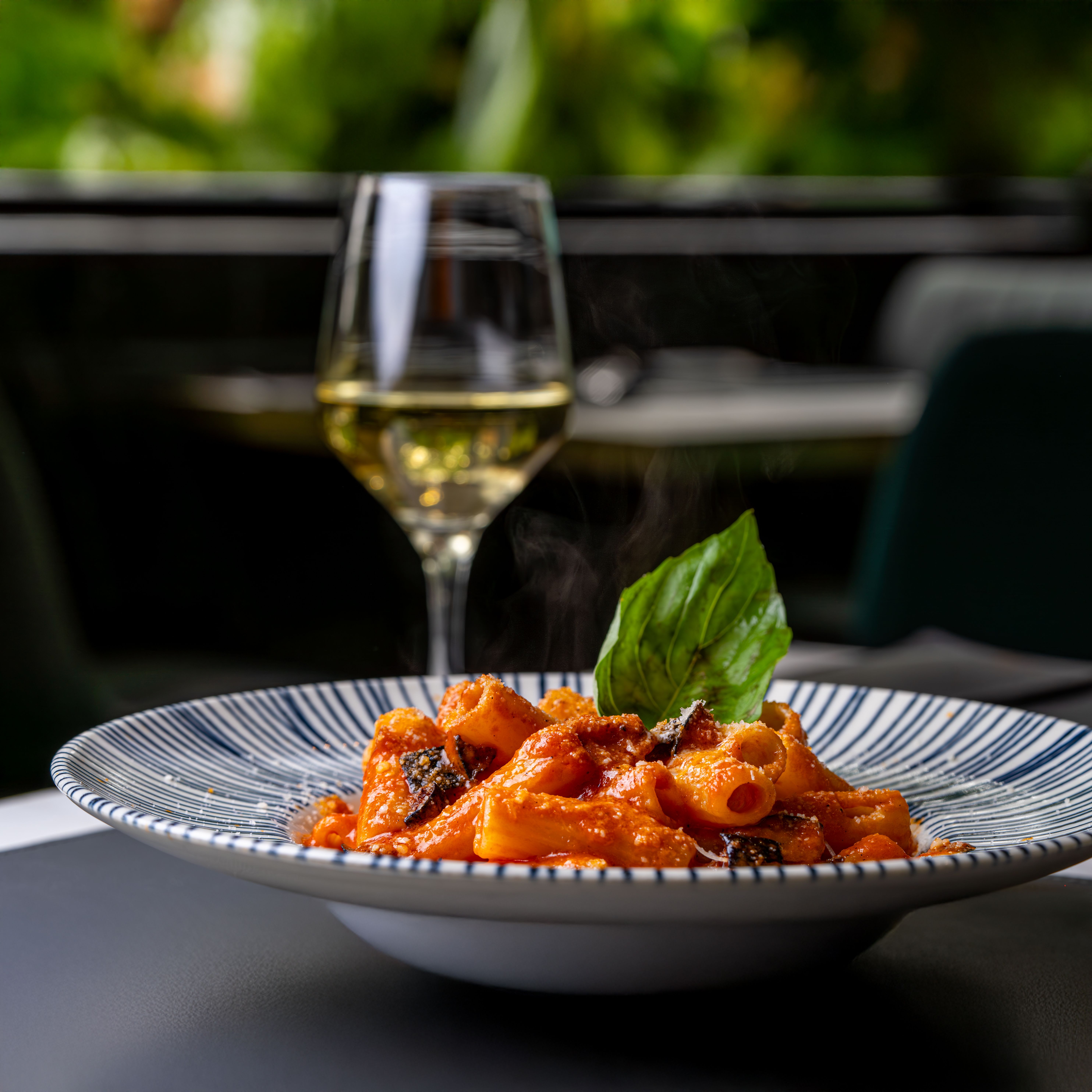 Appetizing rigatoni pasta with tomato sauce and white wine in an elegant setting.
