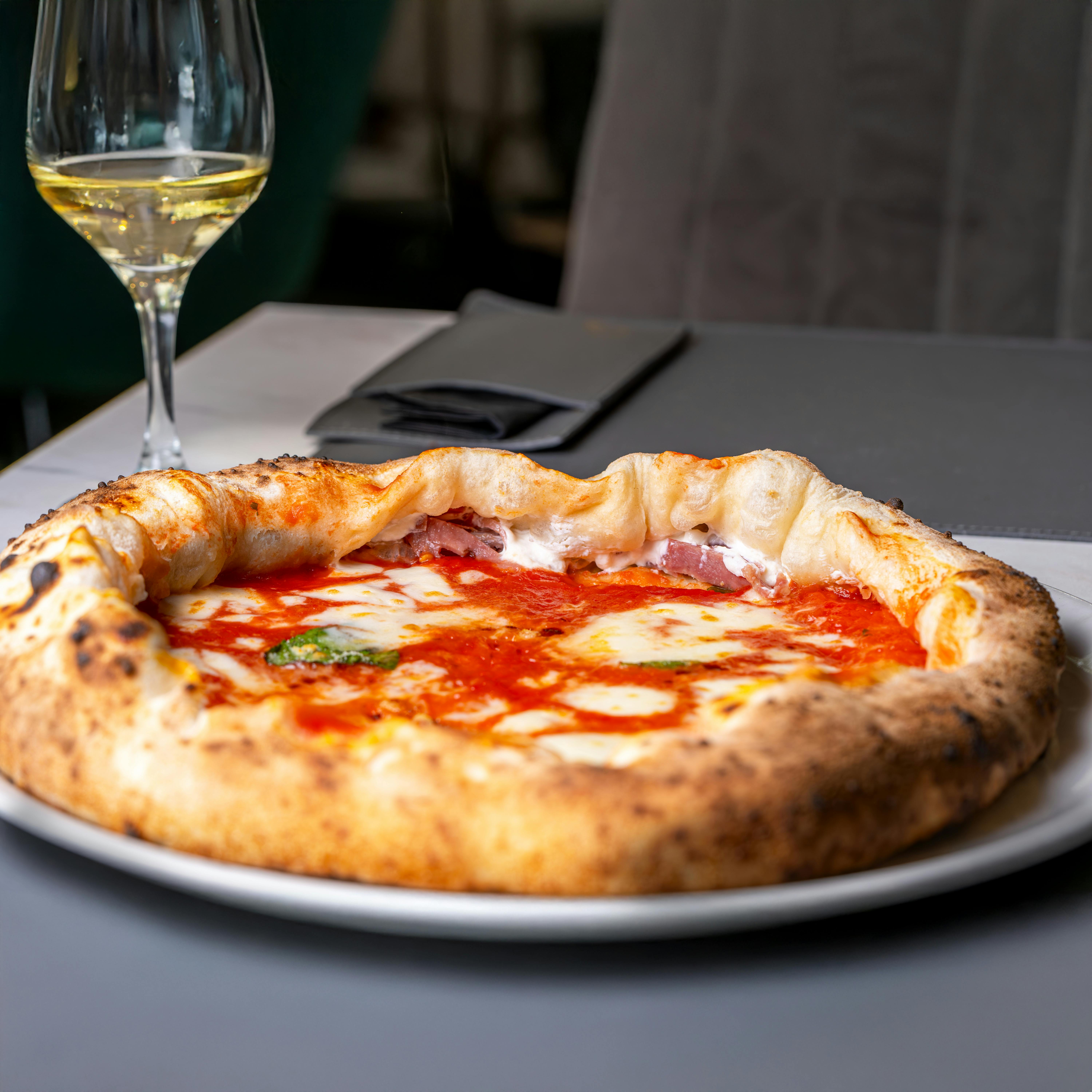 Mouthwatering Neapolitan pizza paired with a glass of white wine, perfect dining experience.