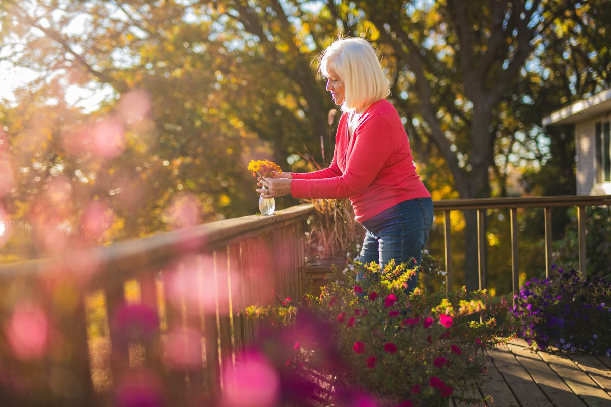 Femme âgée souriante arrangeant des fleurs au soleil