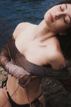 Young woman in swimwear feeling relaxed by the water's edge, enjoying a serene moment.