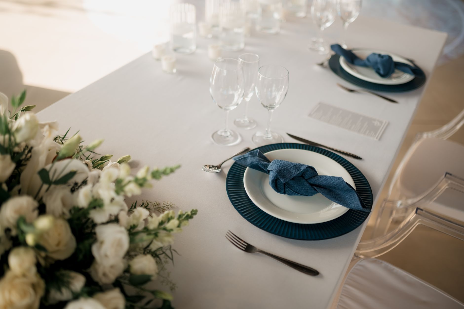 Beautifully arranged wedding table setting with floral design and blue napkins for an elegant celebration.