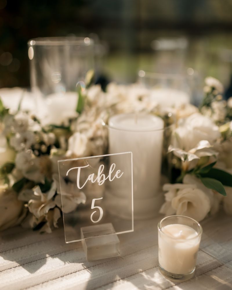 Table setup with candles, white flowers and table number sign