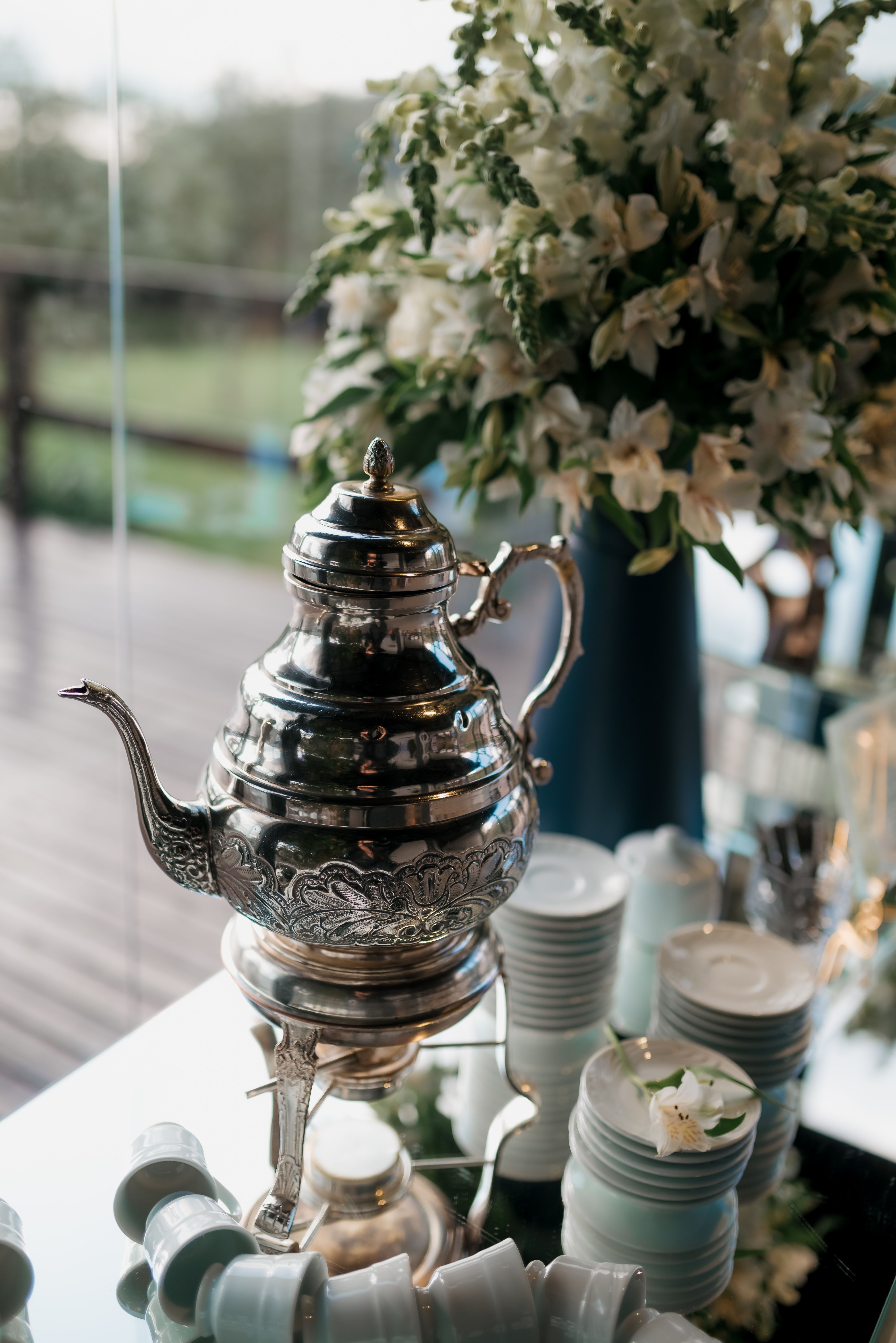 Beautiful silver teapot with cups and floral decoration in an elegant setting.