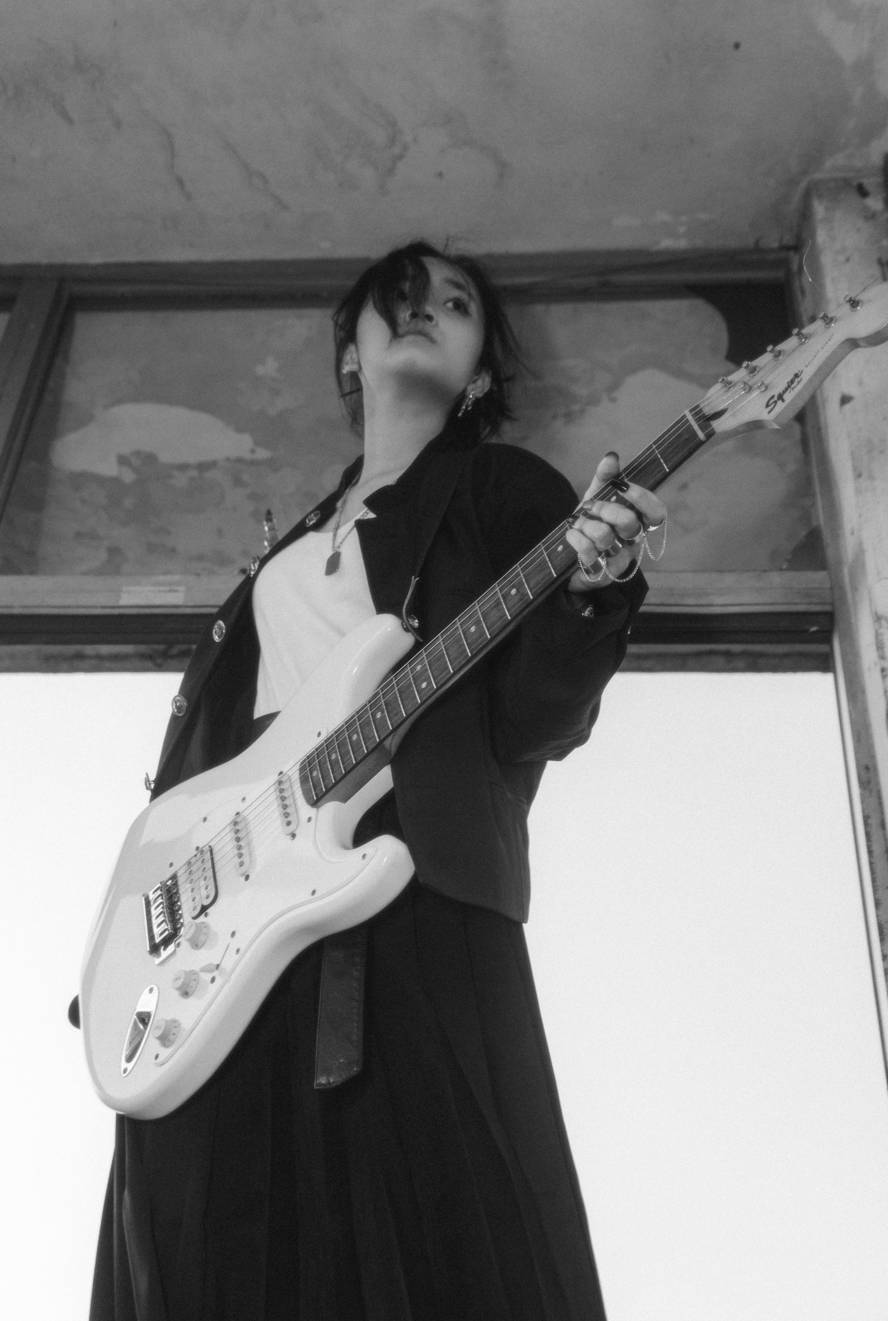 Artistic black and white photo of a musician with an electric guitar in a vintage setting.