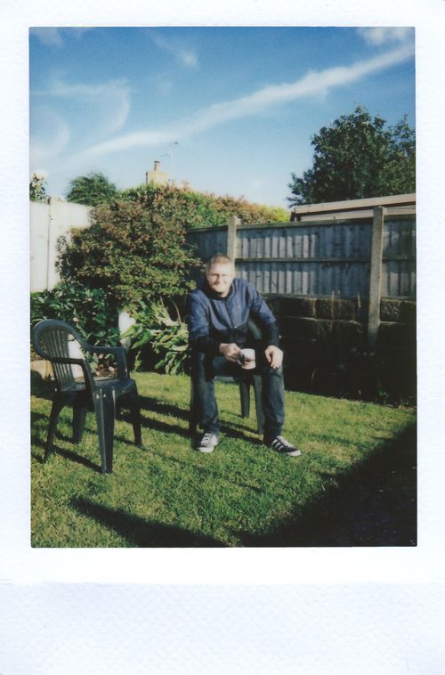 Free A man enjoys a tranquil moment with a cup of tea in a sunny backyard. Stock Photo