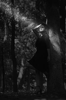 阳光明媚的森林中，一名女子对着一棵树戏剧性地摆出姿势，营造出一种喜怒无常的艺术氛围