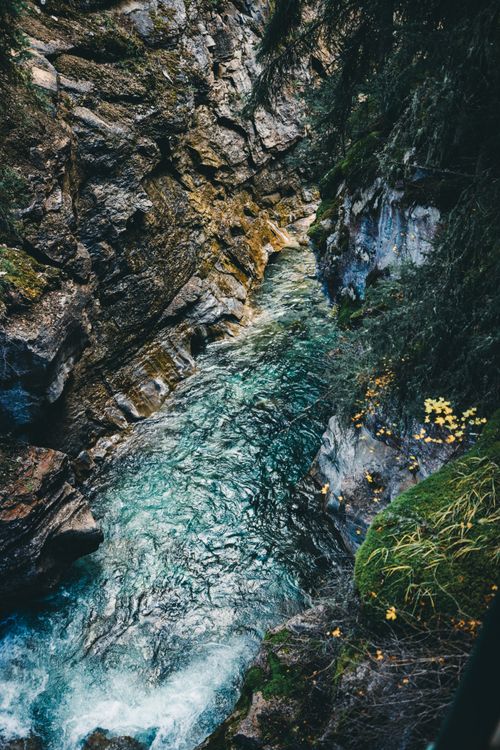 Free Explore the tranquil beauty of a creek flowing through rocky terrain in Banff, Canada. Stock Photo