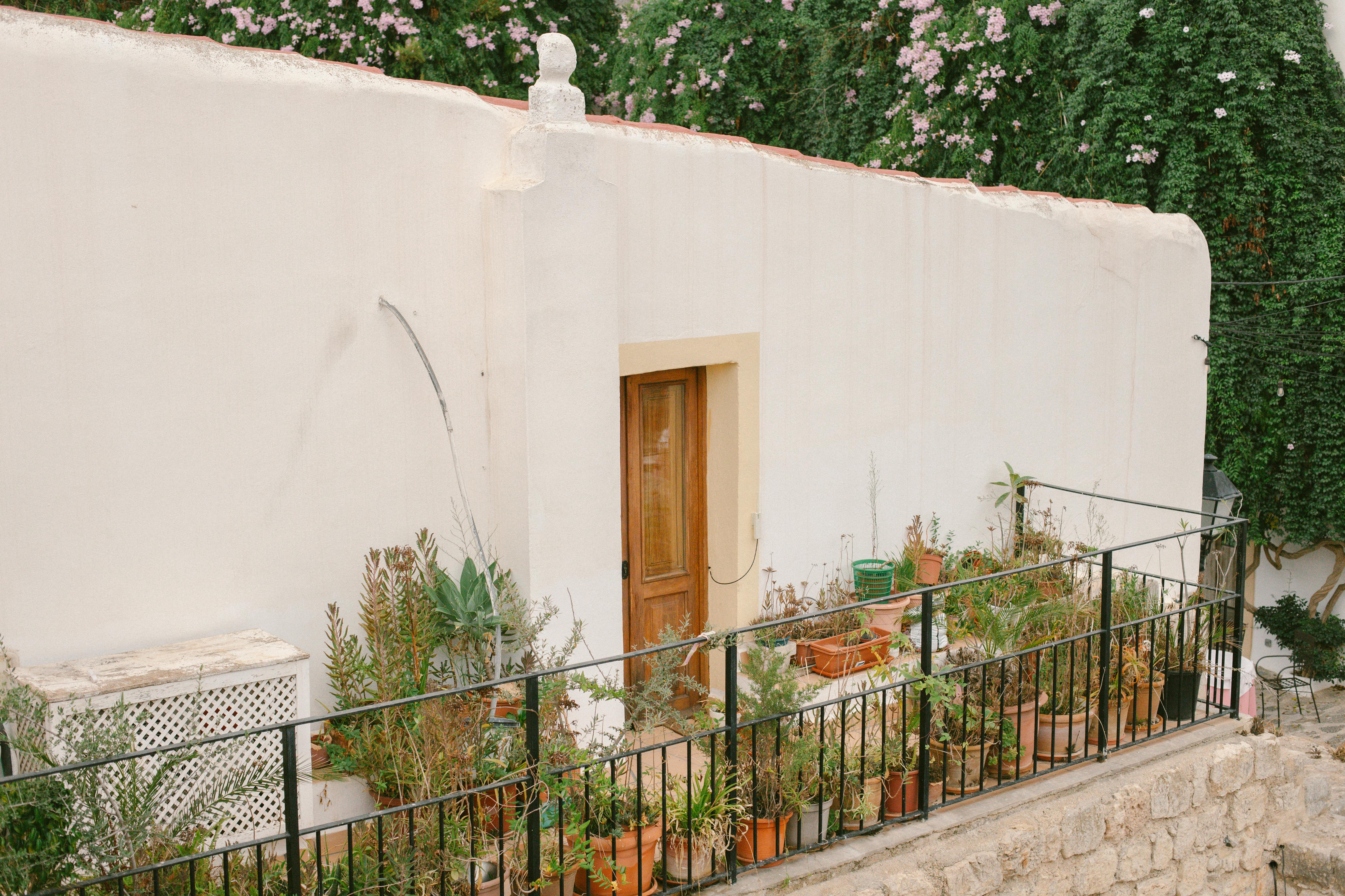 Picturesque Ibiza house with a lush balcony garden, showcasing Mediterranean architecture.