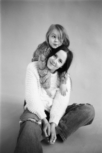 Black and white portrait of a mother and child in cozy knit sweaters, smiling together.