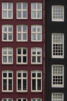A cityscape showing symmetrical red and black building facades with multiple windows.