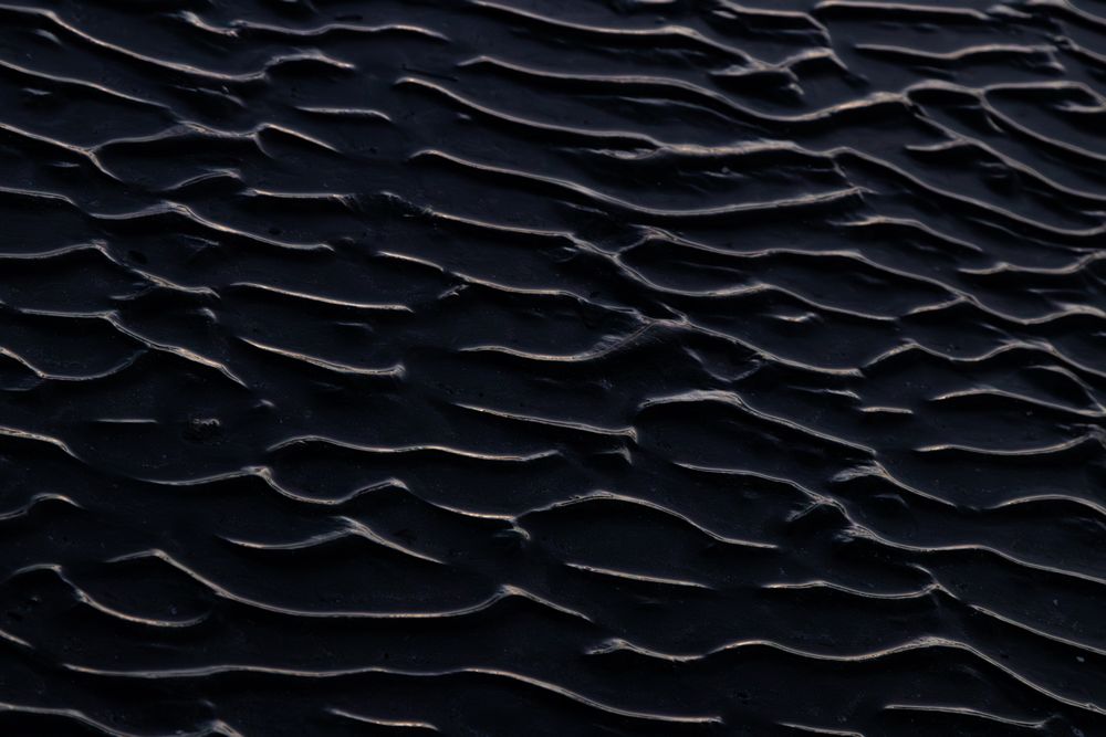 Dark sand ripples forming an abstract texture — photo by Diego Fraga on Pexels