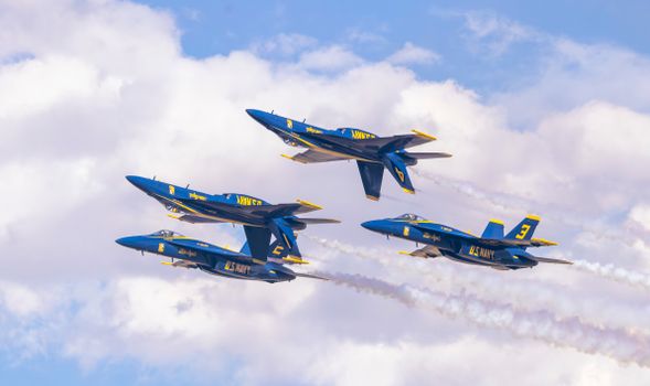US Navy Blue Angels jets in precise aerobatic formation against a clear sky.