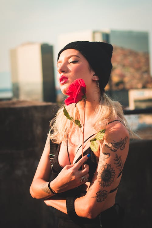 검은 옷에 문신을 한 여자와 붉은 꽃을 들고 비니 모자의 선택적 초점 사진
