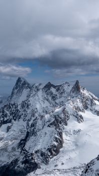 Majestic view of snow-covered peaks of Mont Blanc in Chamonix, France under a cloudy sky.