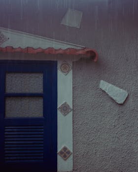 Moody image of a blue-framed door in rainy weather, showcasing vintage architecture.