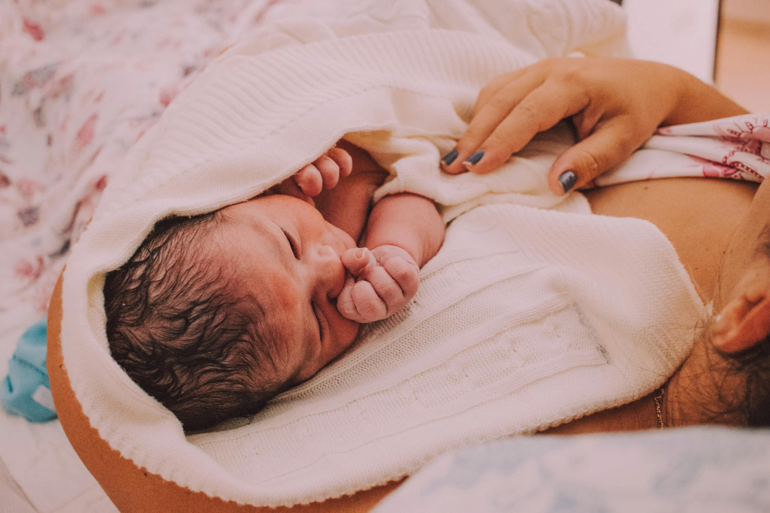 A newborn wrapped in a blanket, cradled gently in mother's arms, evoking warmth and love.