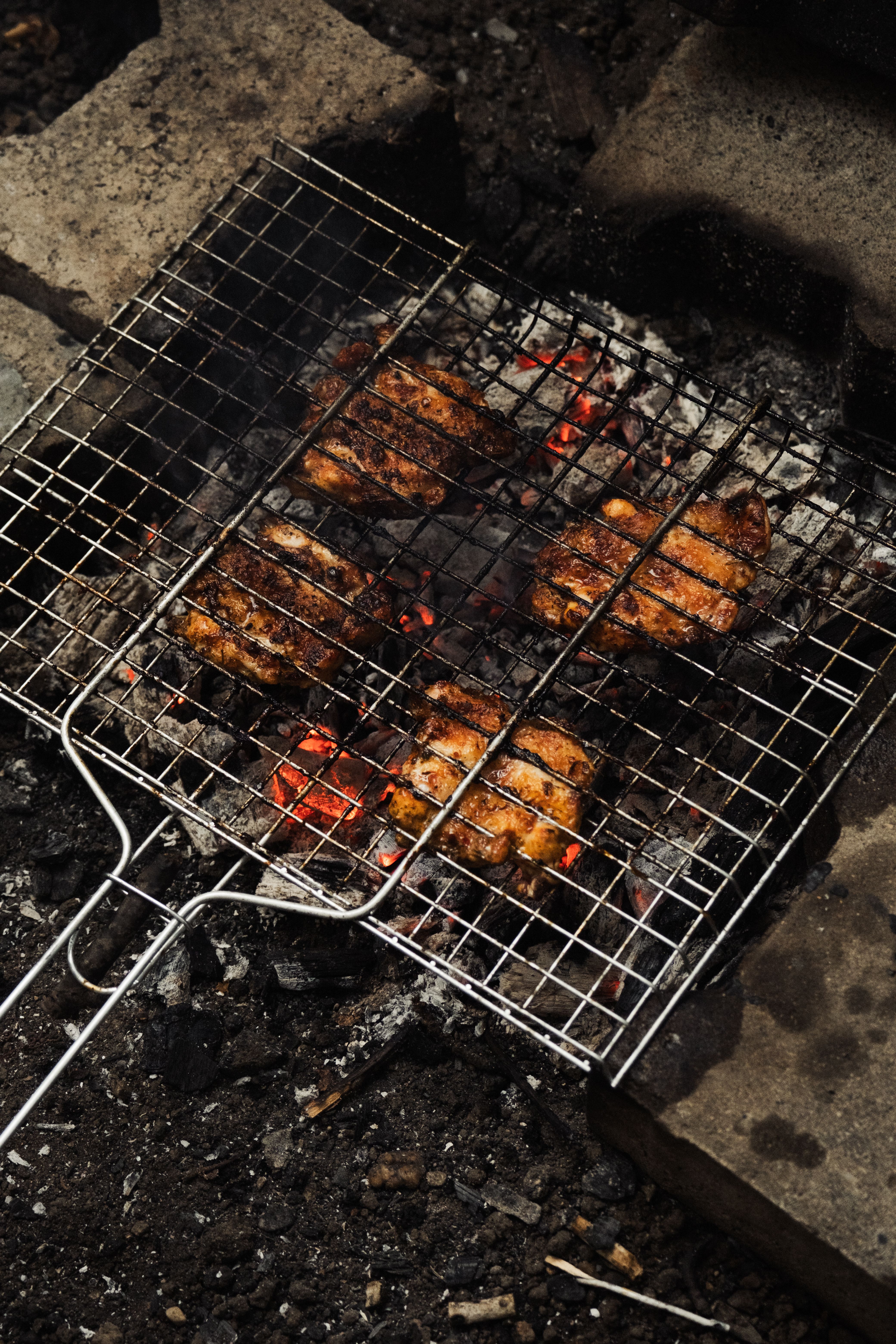 Close-up of grilled chicken cooking on a charcoal barbecue grill outdoors.