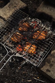 Close-up of grilled chicken cooking on a charcoal barbecue grill outdoors.