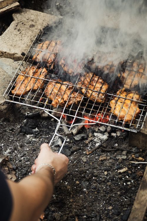 Free Close-up of marinated chicken being grilled over open charcoal fire outdoors. Stock Photo