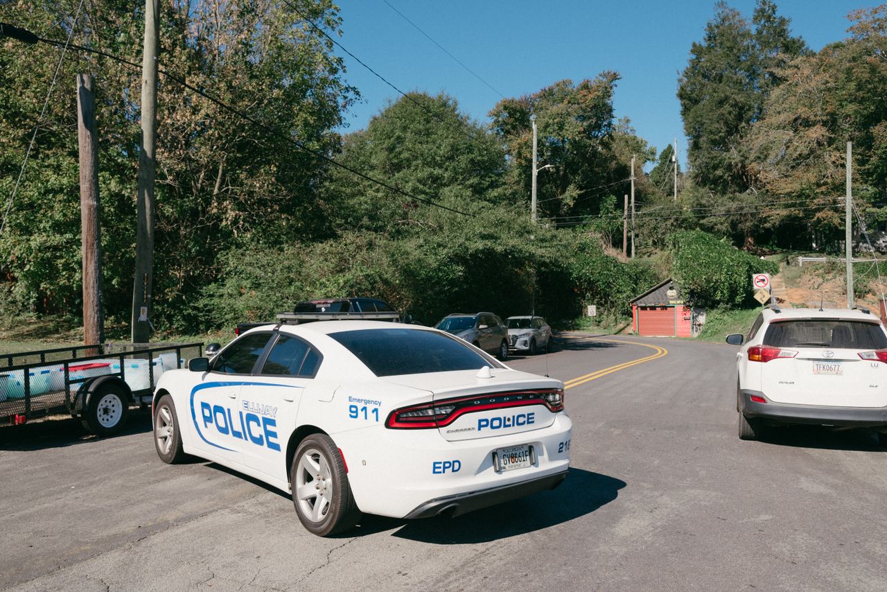 a police car parked at a suburban road intersection on a sunny day