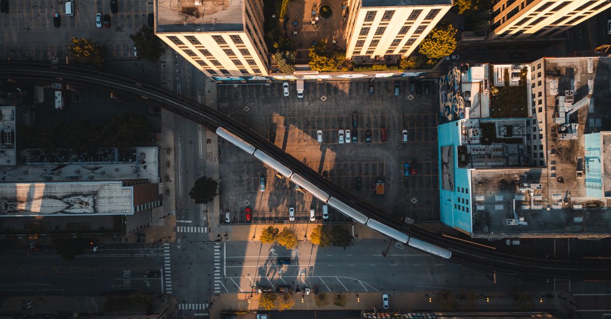Aerial shot of a cityscape with a train passing through buildings at sunset. Urban infrastructure and transit theme.