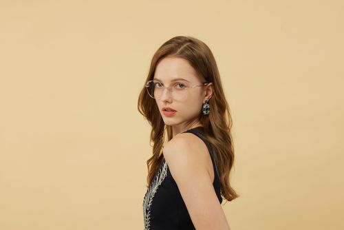 Free Portrait of a stylish woman wearing glasses and earrings on a beige background. Stock Photo