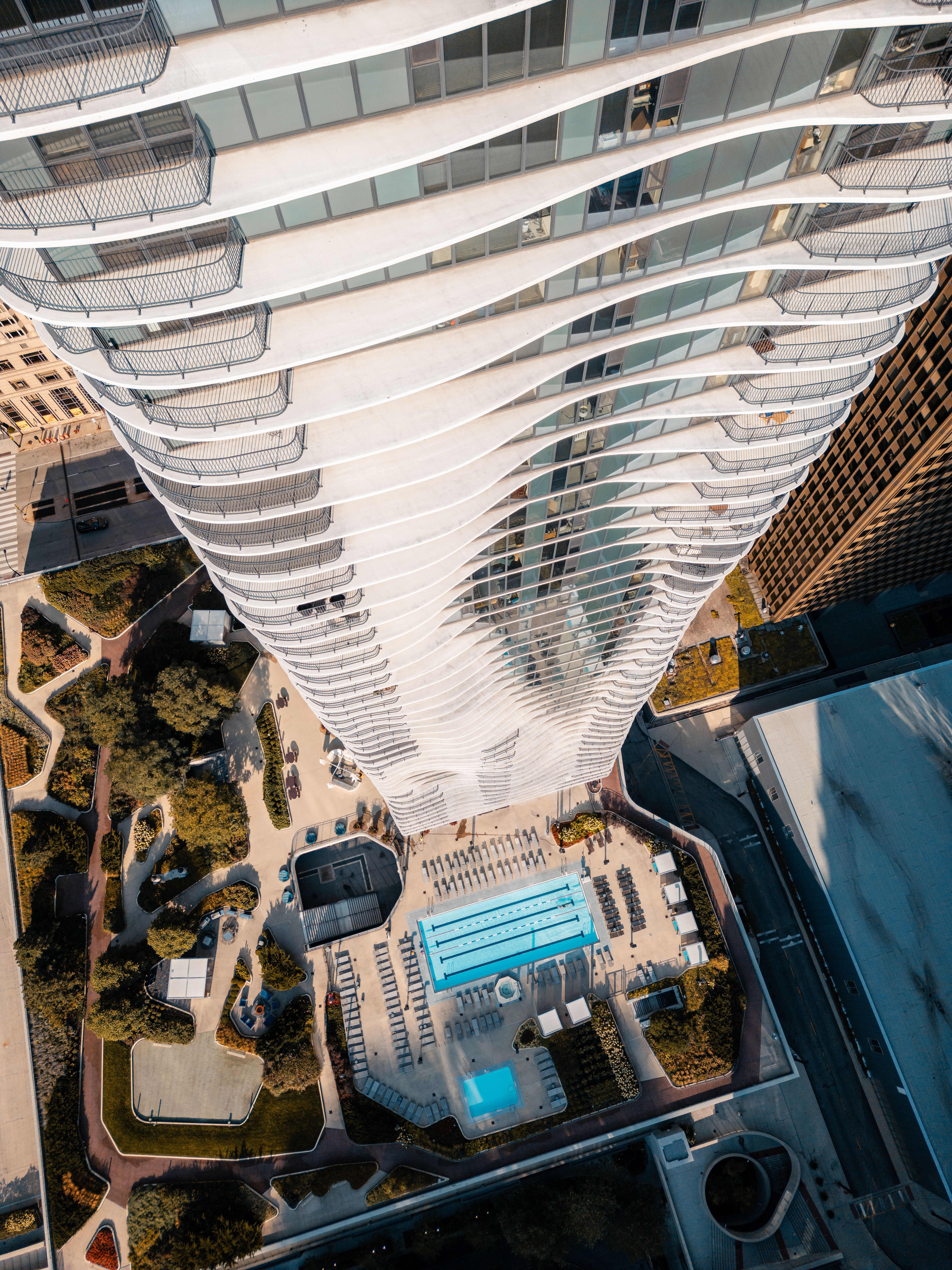 Dramatic aerial shot of a contemporary skyscraper and pool area in a cityscape.