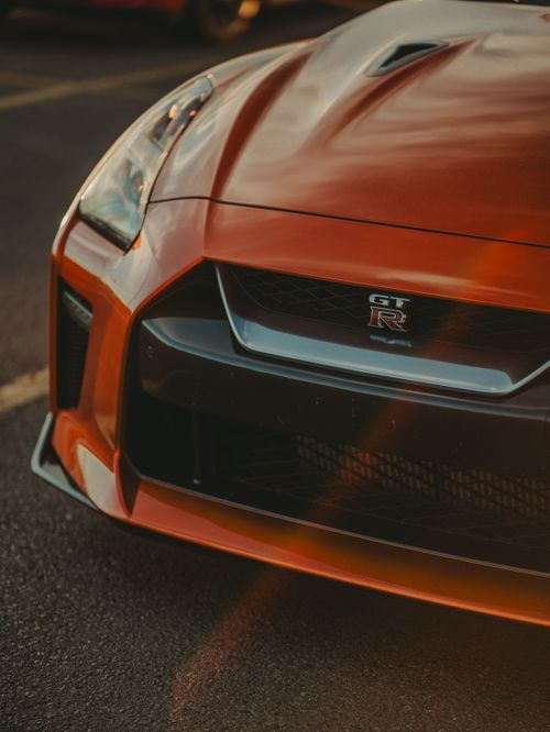 Free Dynamic close-up shot of a Nissan GT-R car with sunlight reflections highlighting the design. Stock Photo