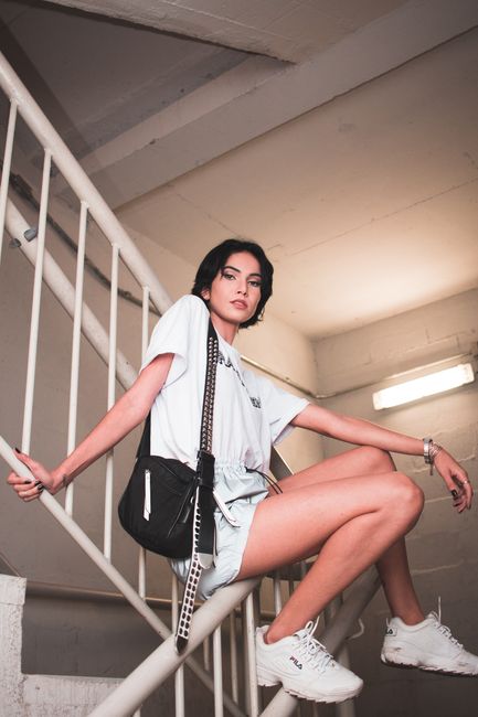 Fashionable woman in casual wear poses confidently on an industrial stairwell indoors.