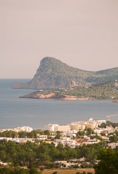 A beautiful coastal view of Ibiza showcasing its Mediterranean charm with picturesque hills and seashore.