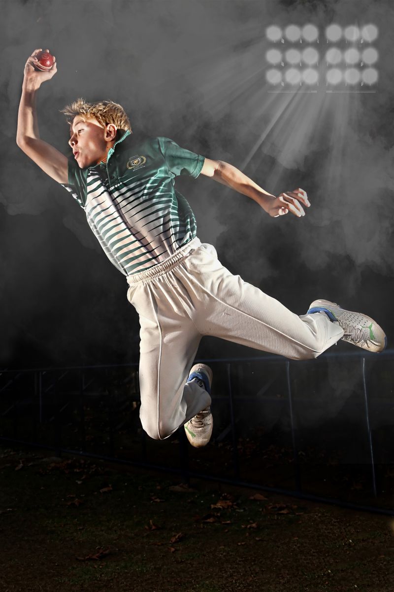 Bowler mid-air delivering under floodlights
