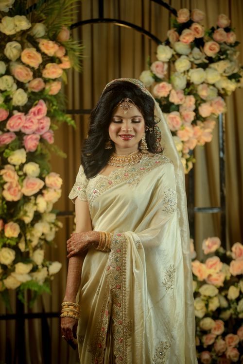 Free An Indian bride in a saree, posing elegantly amidst lush floral decorations. Stock Photo