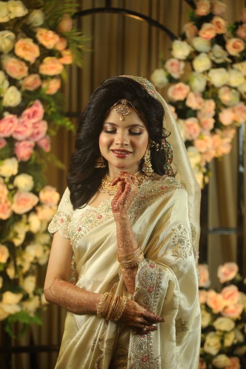 Free Beautiful Indian bride in ornate traditional attire with henna, captured indoors adorned with floral decorations. Stock Photo