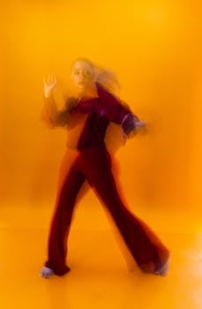 Artistic capture of a dancer in motion against an orange backdrop, exhibiting dynamic blur effects.