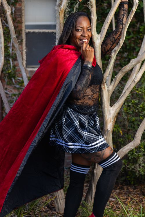 Free Portrait of a woman in a red cape posing confidently outdoors in Winter Park, Florida. Stock Photo