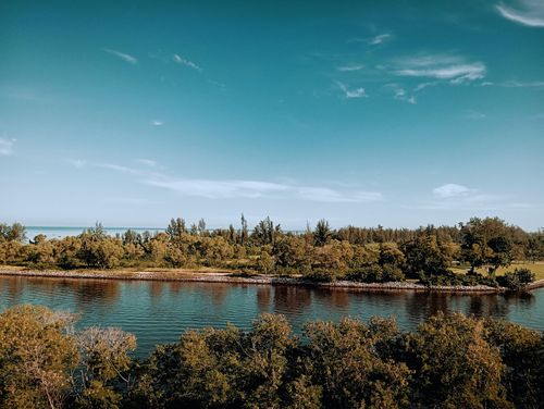 Free A tranquil view of a river with surrounding lush greenery under a clear blue sky. Stock Photo