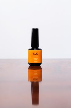 Minimalist photo of an orange-labeled bottle on a glossy surface with reflection.