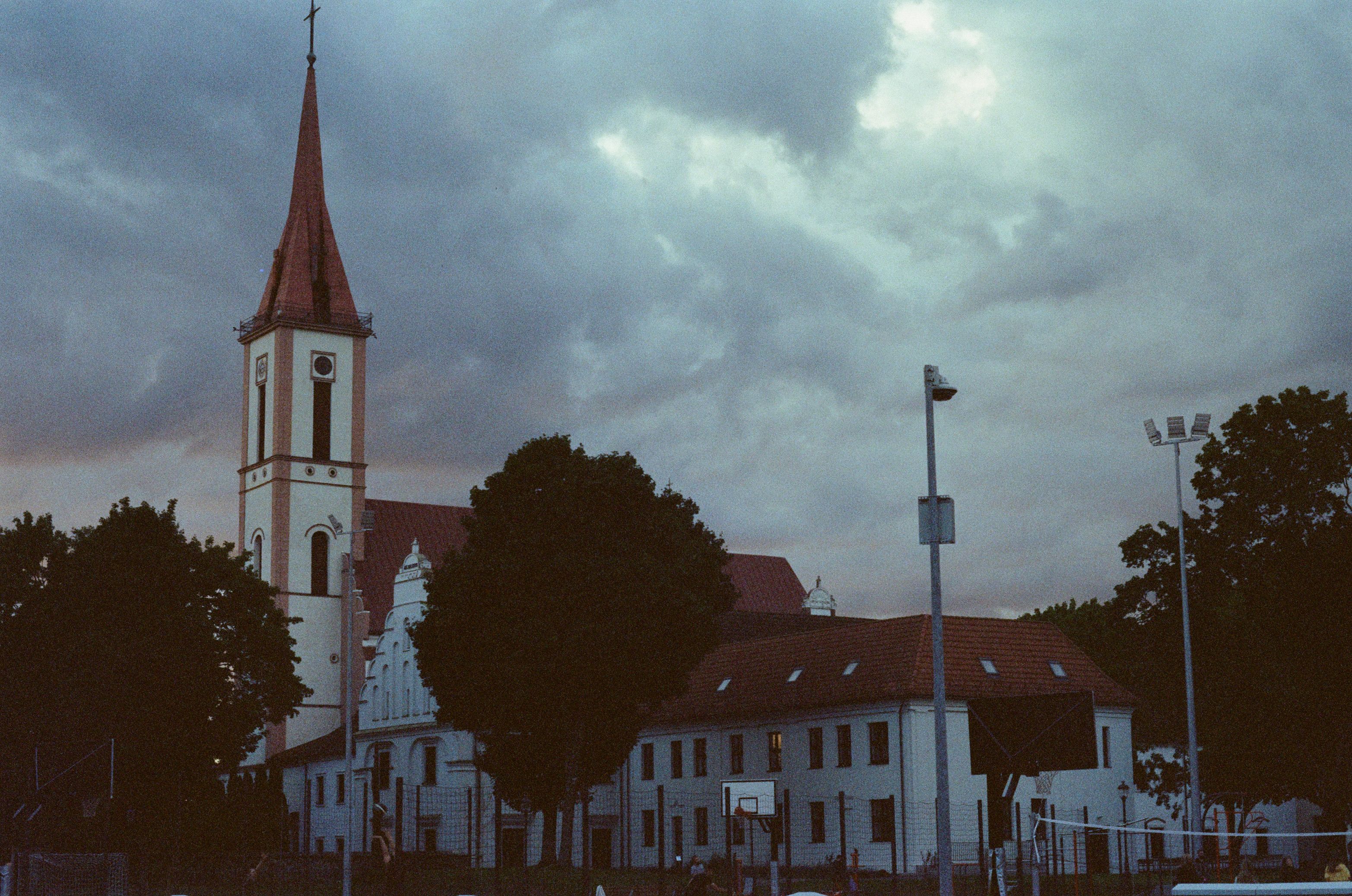 A twilight view of a historic church in Kretinga, Lithuania, with dramatic skies.